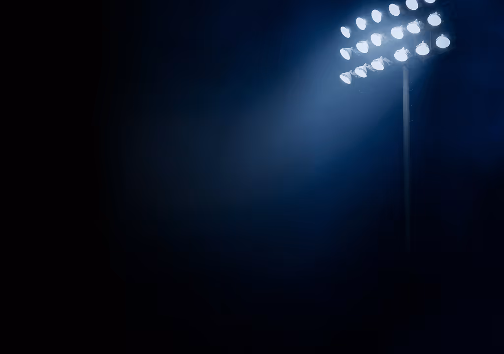 Bright stadium floodlights illuminating a dark night sky.