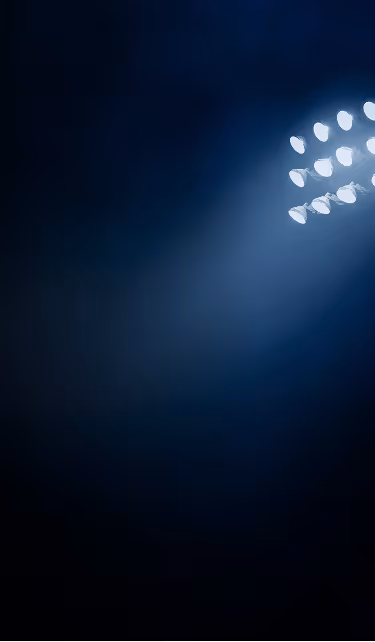 Bright stadium floodlights shining against a dark night sky.