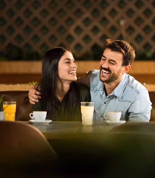 Smiling man and woman enjoying frozen yogurt treats in front of a llaollao store.
