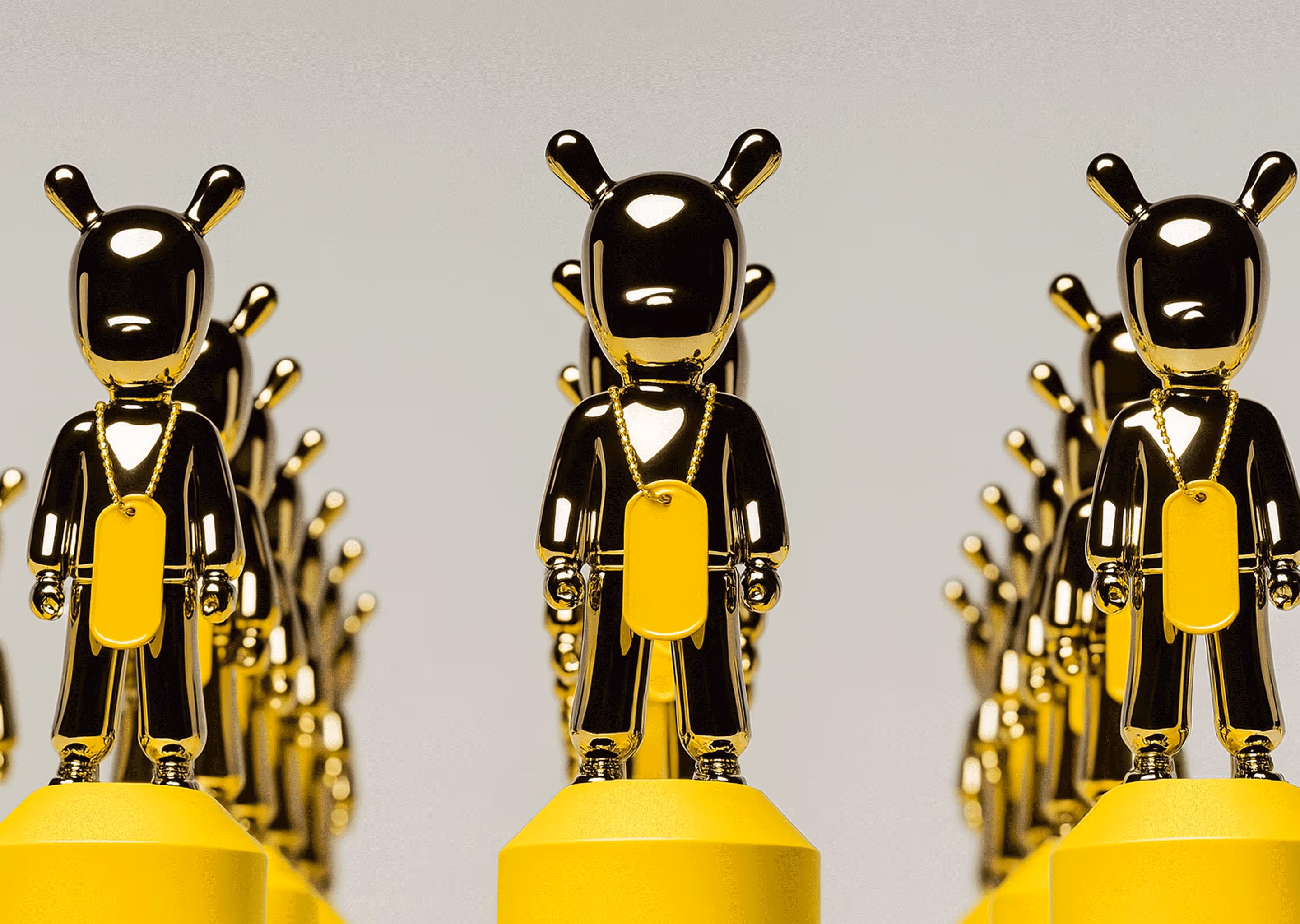 Rows of shiny golden figurines with bear-like ears, each wearing a gold chain with a yellow tag, standing on yellow pedestals.