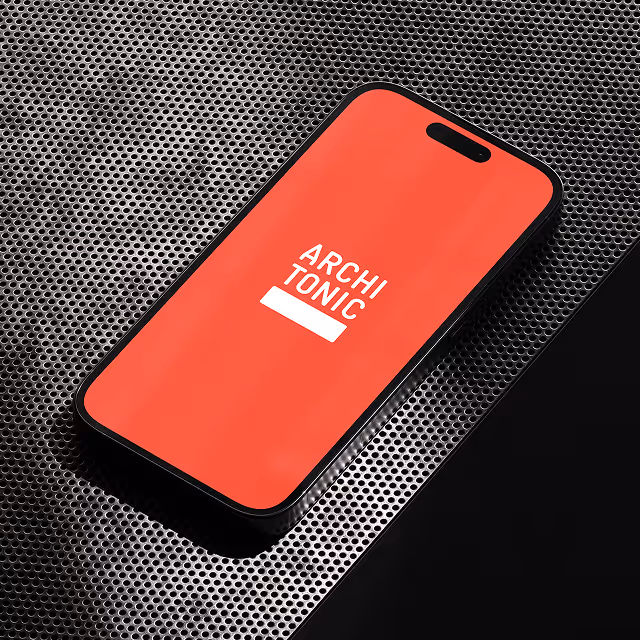 Smartphone with a red screen displaying the white text 'ARCHI TONIC' resting on a perforated metal surface.
