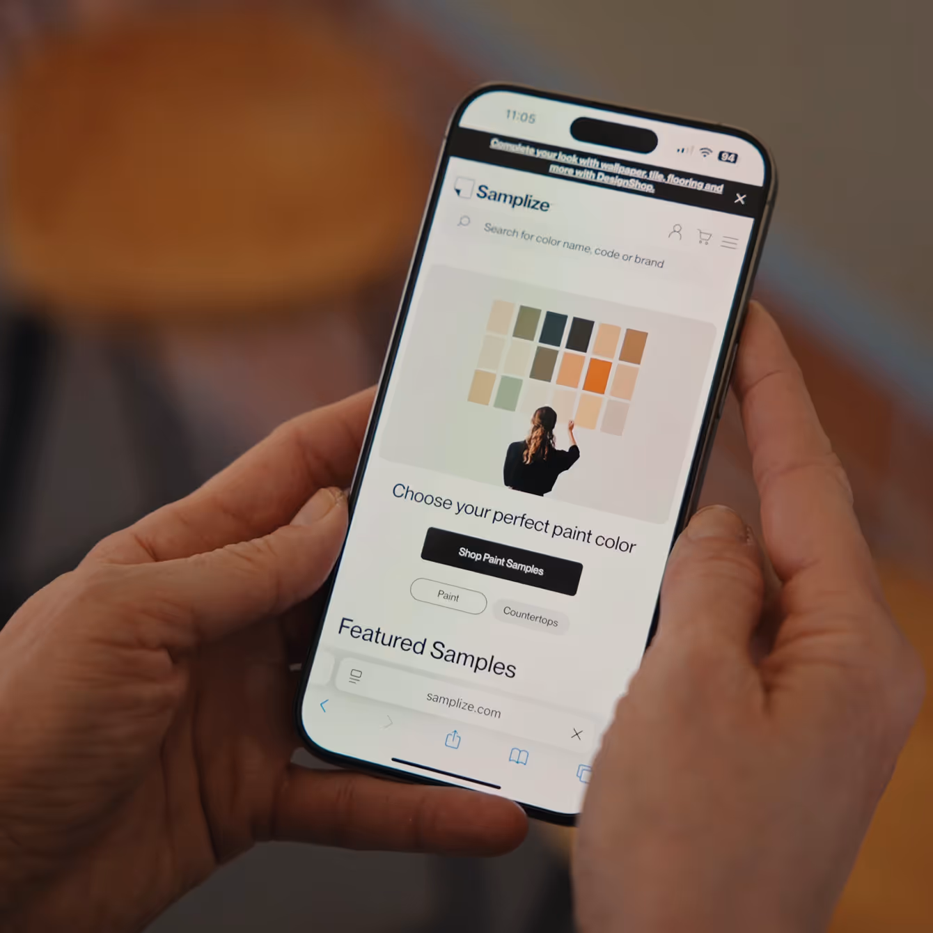 Person holding a smartphone displaying Samplize website with options to choose paint colors and shop paint samples.