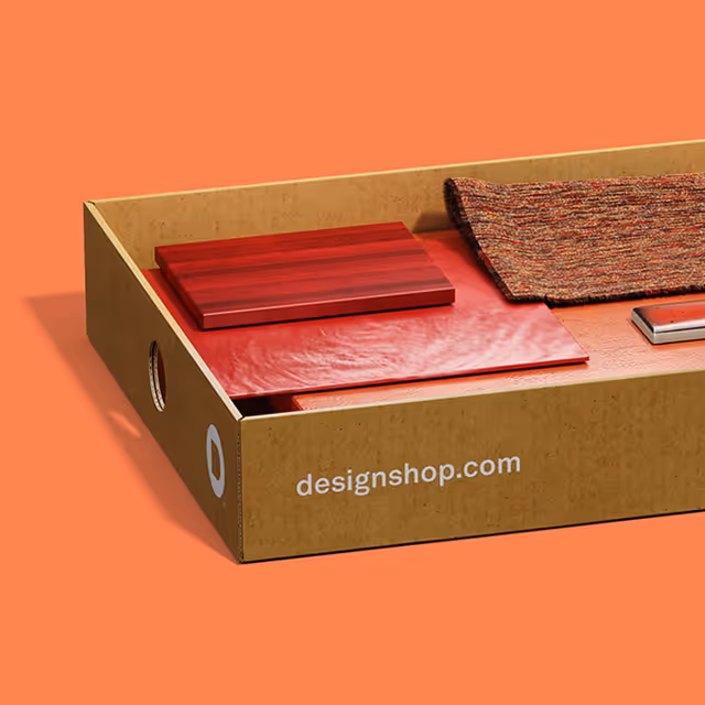Open cardboard box containing red material samples and a woven fabric piece on an orange background.
