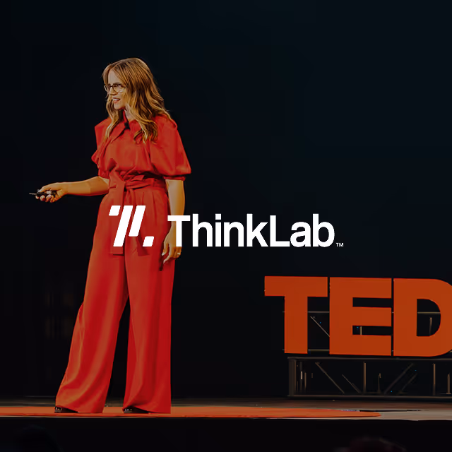 Woman in red outfit giving a TED Talk on stage with ThinkLab logo.