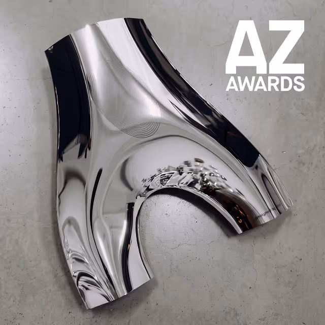 Shiny, reflective silver abstract sculpture on a gray concrete surface with 'AZ AWARDS' text in white on the top right.