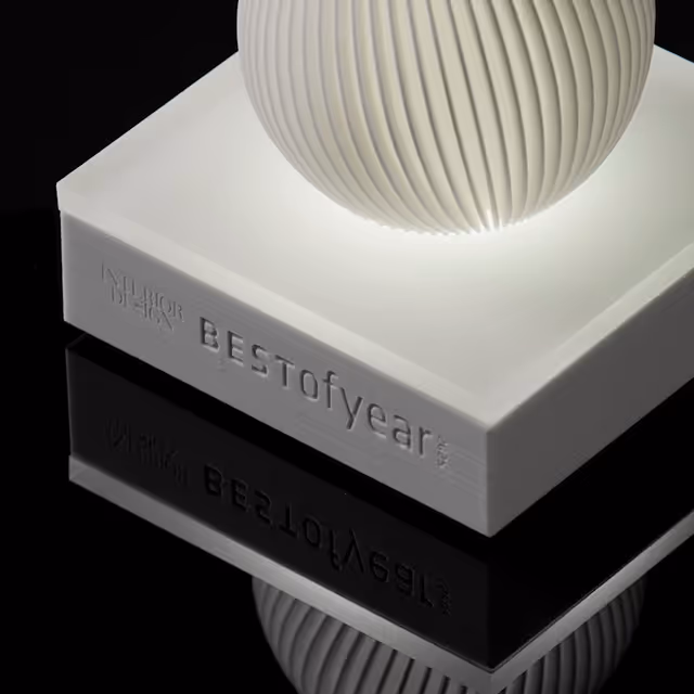 Close-up of a white rectangular award trophy with a vertically ribbed sphere on top and the inscription 'BESTofyear' on the side.