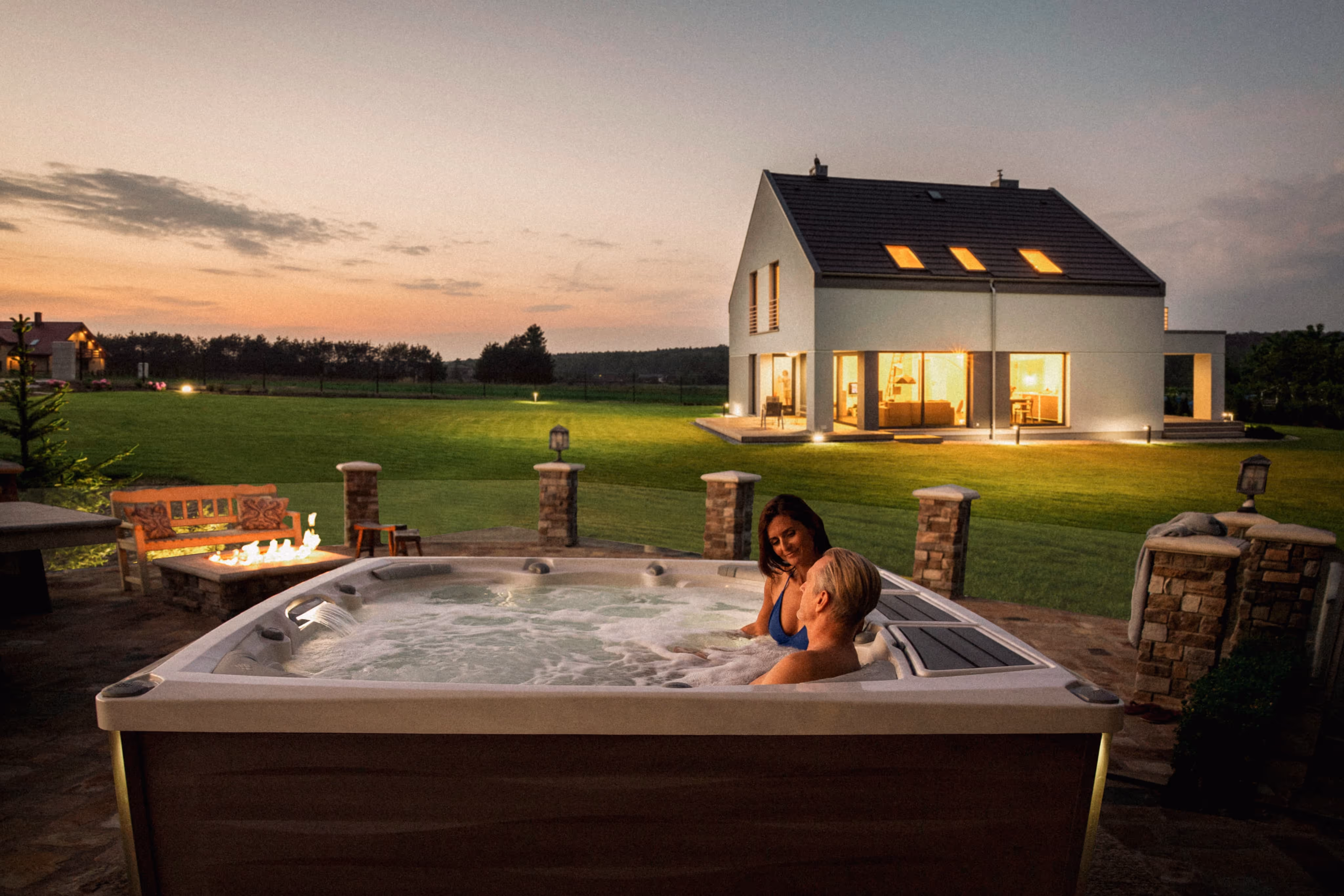 Couple enjoying a hot tub on a patio overlooking a house and large yard