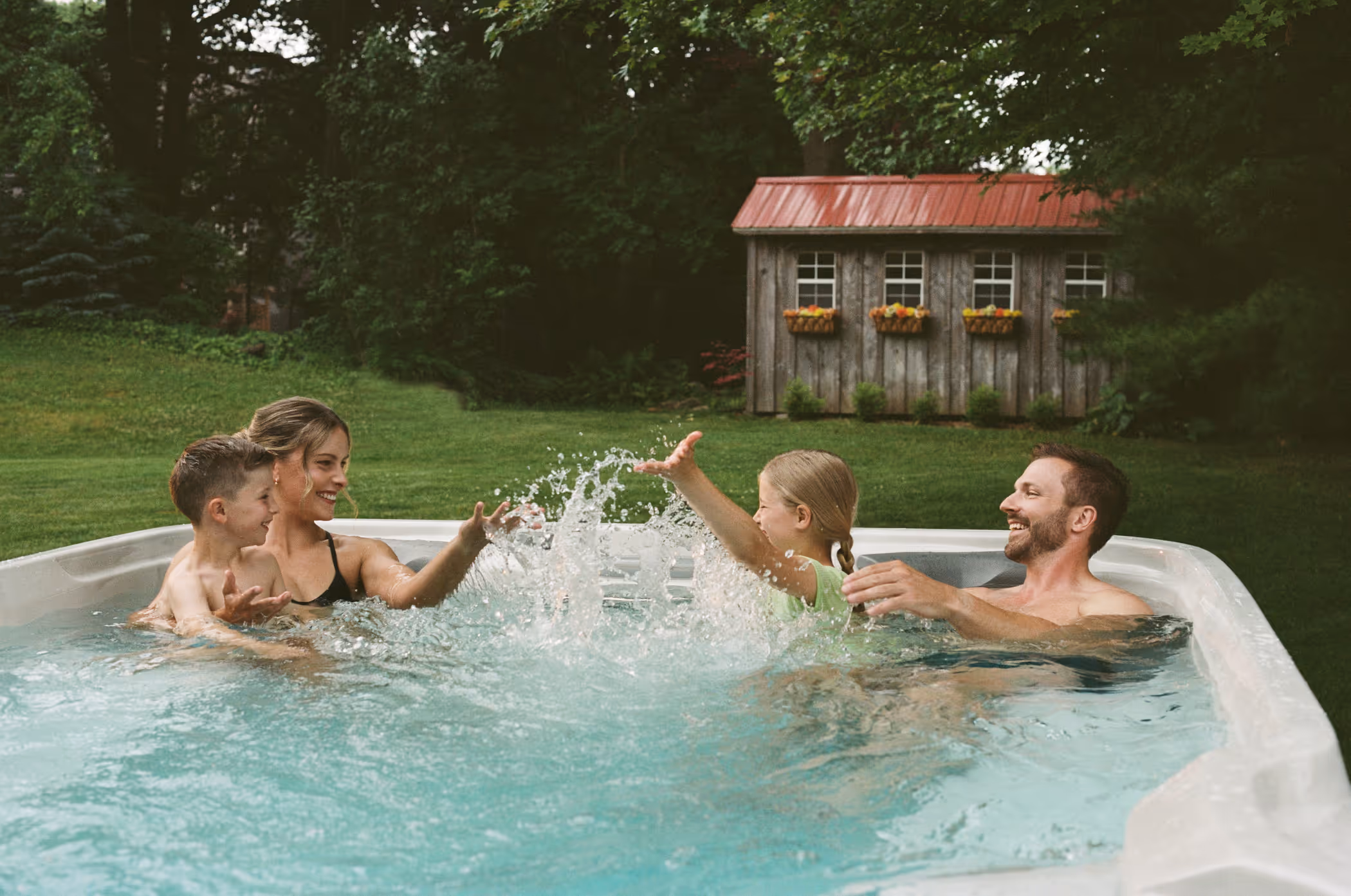 Young family splashing and playing together in a Sundance swim spa