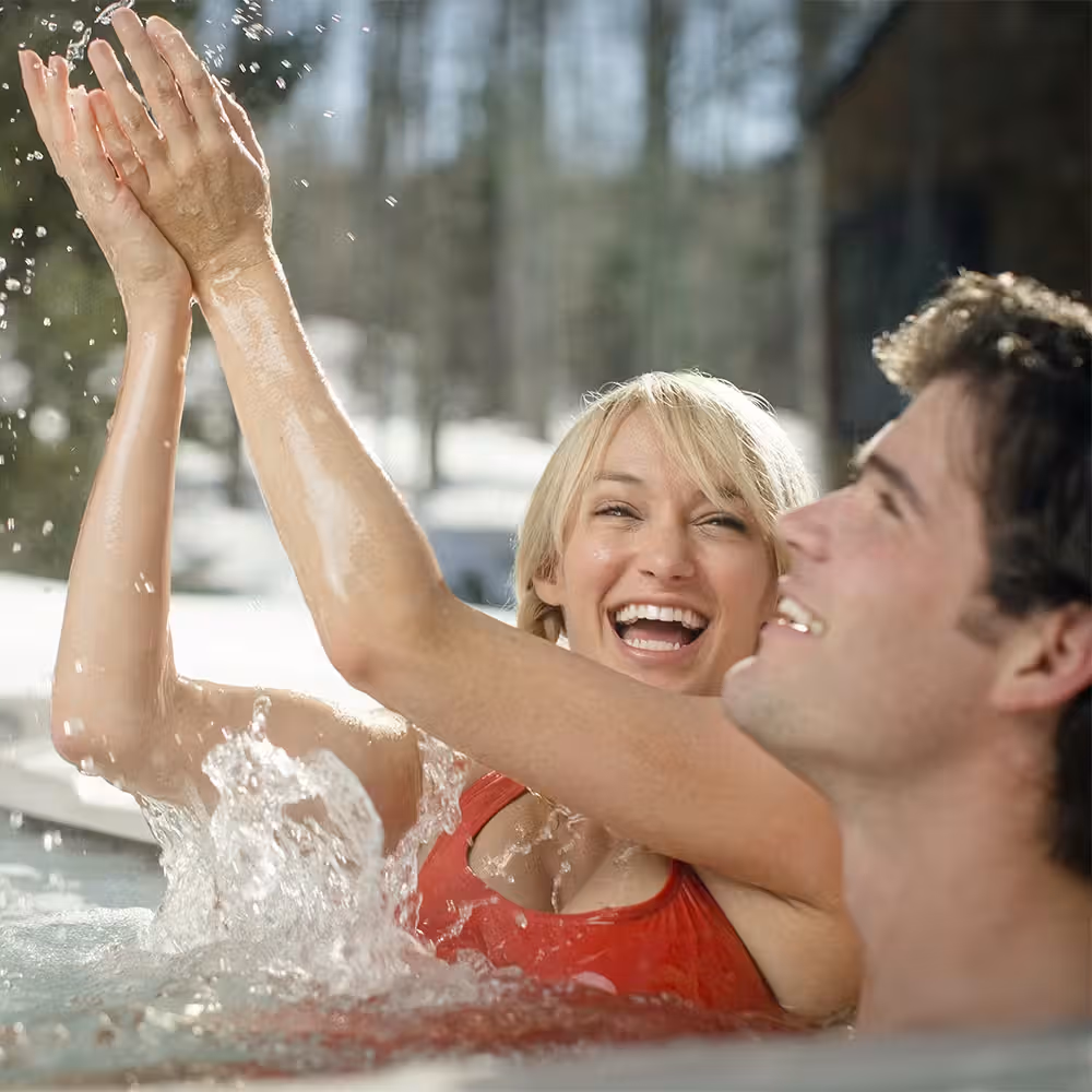 Couple playfully tossing water in a hot tub