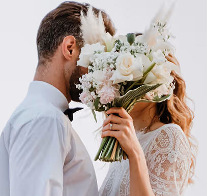 Pareja de boda con ramo floral en ceremonia elegante al aire libre