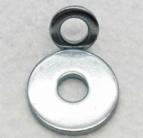 Two metal washers stacked, one small and one large, on a light surface.