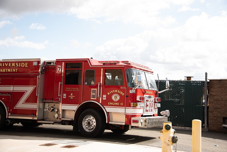 Red Riverside fire truck labeled Engine 11 parked outside near a fire hydrant on a sunny day.