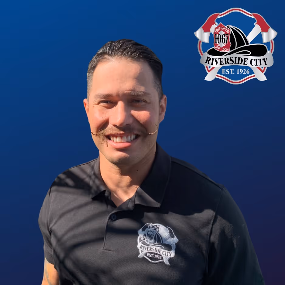 Smiling man with styled mustache wearing a black Riverside City Firefighters polo shirt against a blue background with the Riverside City Firefighters logo.