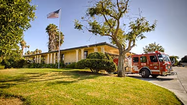 Fire station building with an American flag and a red fire truck parked outside on a sunny day.