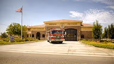 Fire truck parked in front of Northside Fire Station building with clear sky and American flag nearby.