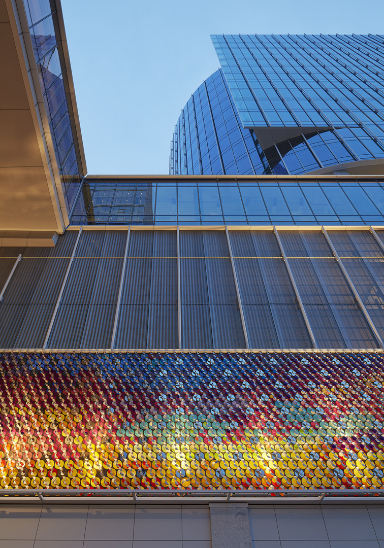 Low-angle view of modern glass buildings with a colorful reflective mosaic panel on the facade.