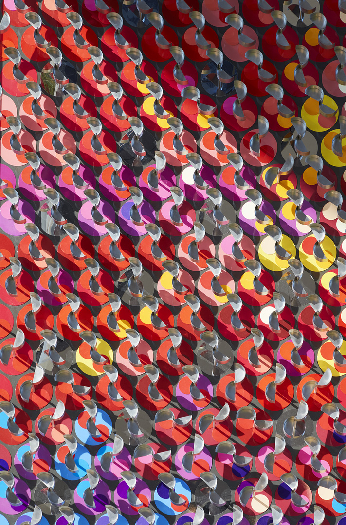 Close-up of colorful overlapping circular discs with metal loops, creating a vibrant geometric pattern.