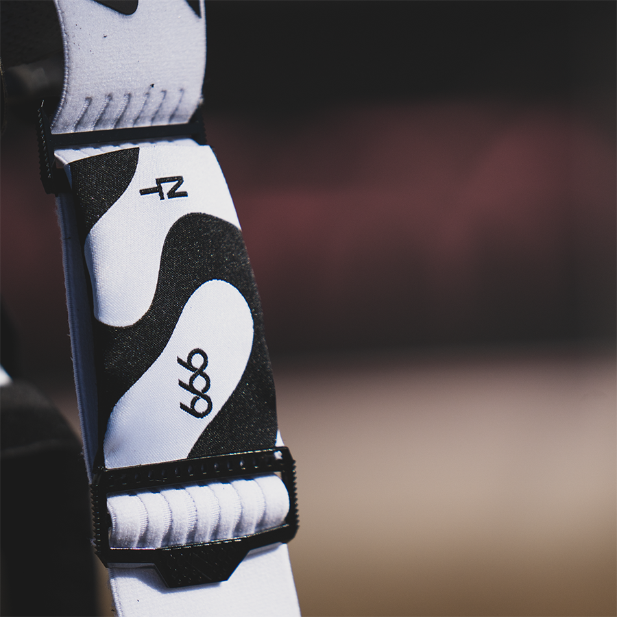 Close-up of a white and black fabric goggle strap with 999  printed on it, secured with a black plastic buckle for Nick Tomasunas