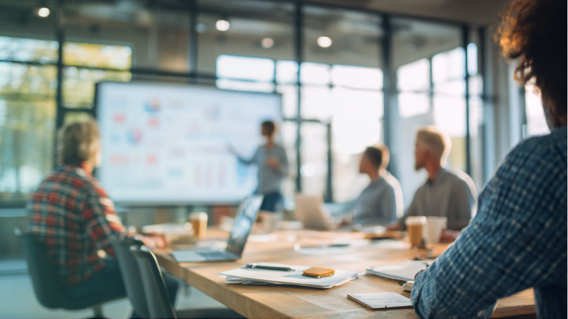 Personne donnant une présentation devant un écran dans une salle de réunion avec plusieurs participants. Réunion de conseil juridique pour dirigeants d'organismes de formation