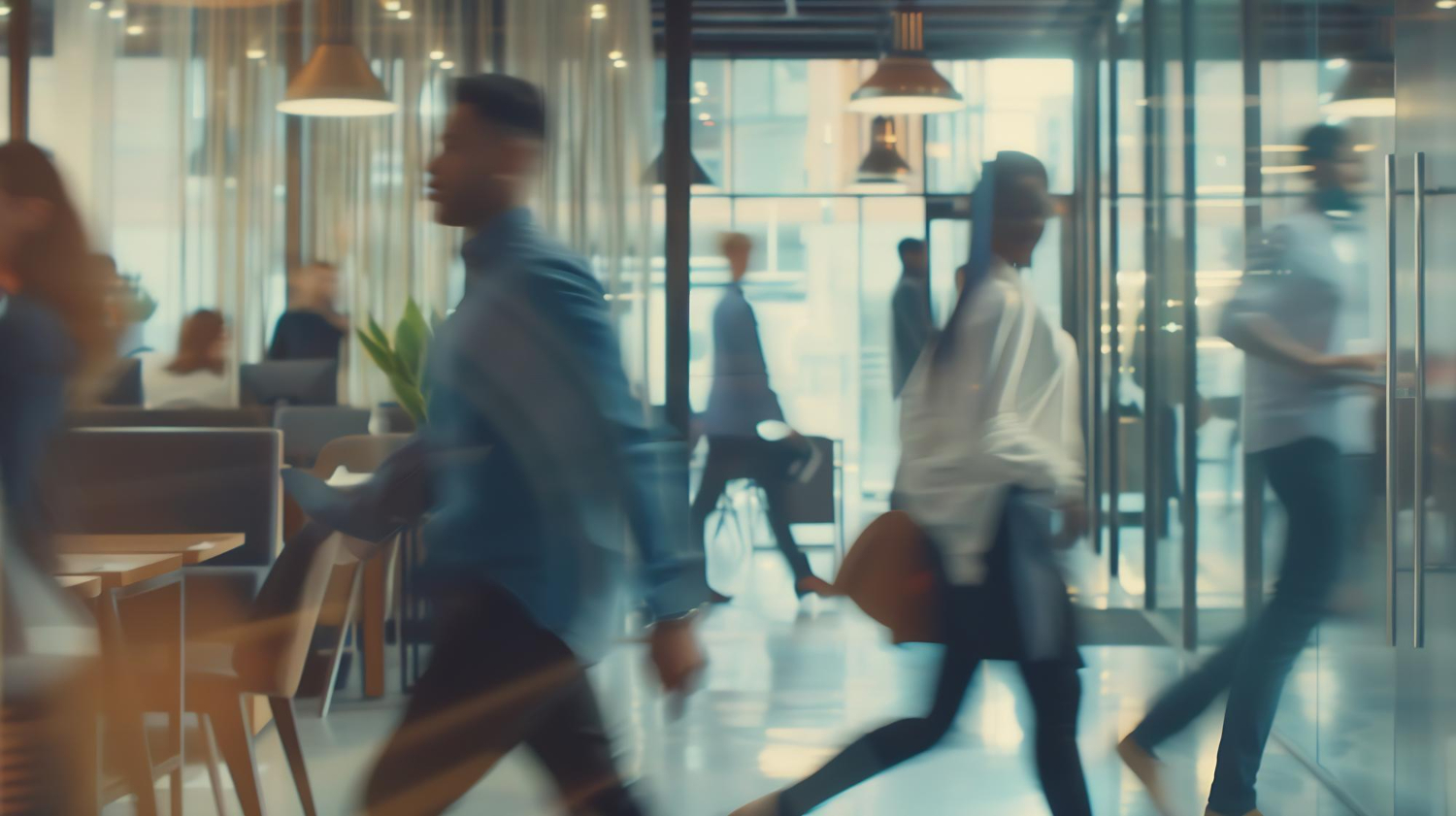 Professionnels en mouvement dans un espace de travail vitré.