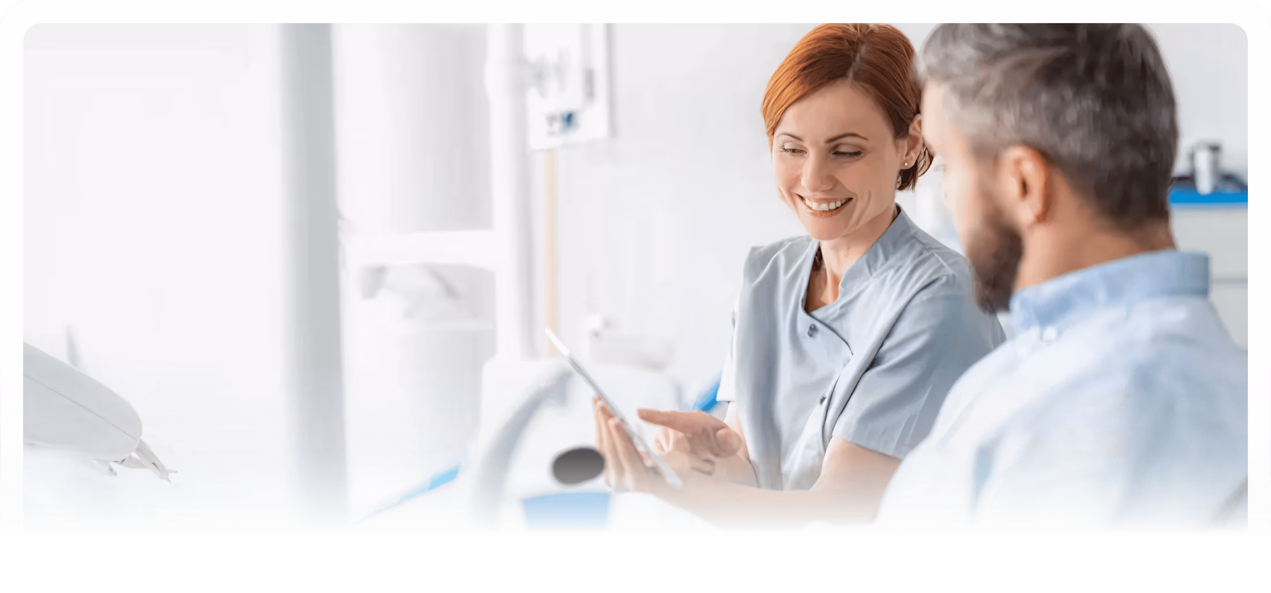 Smiling female healthcare professional showing a tablet to a male patient in a bright medical office.
