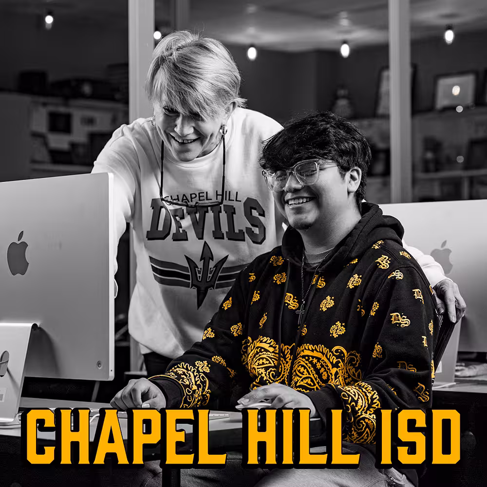 Teacher standing and smiling next to a student sitting at a computer in a classroom, with the text 'CHAPEL HILL ISD' at the bottom.