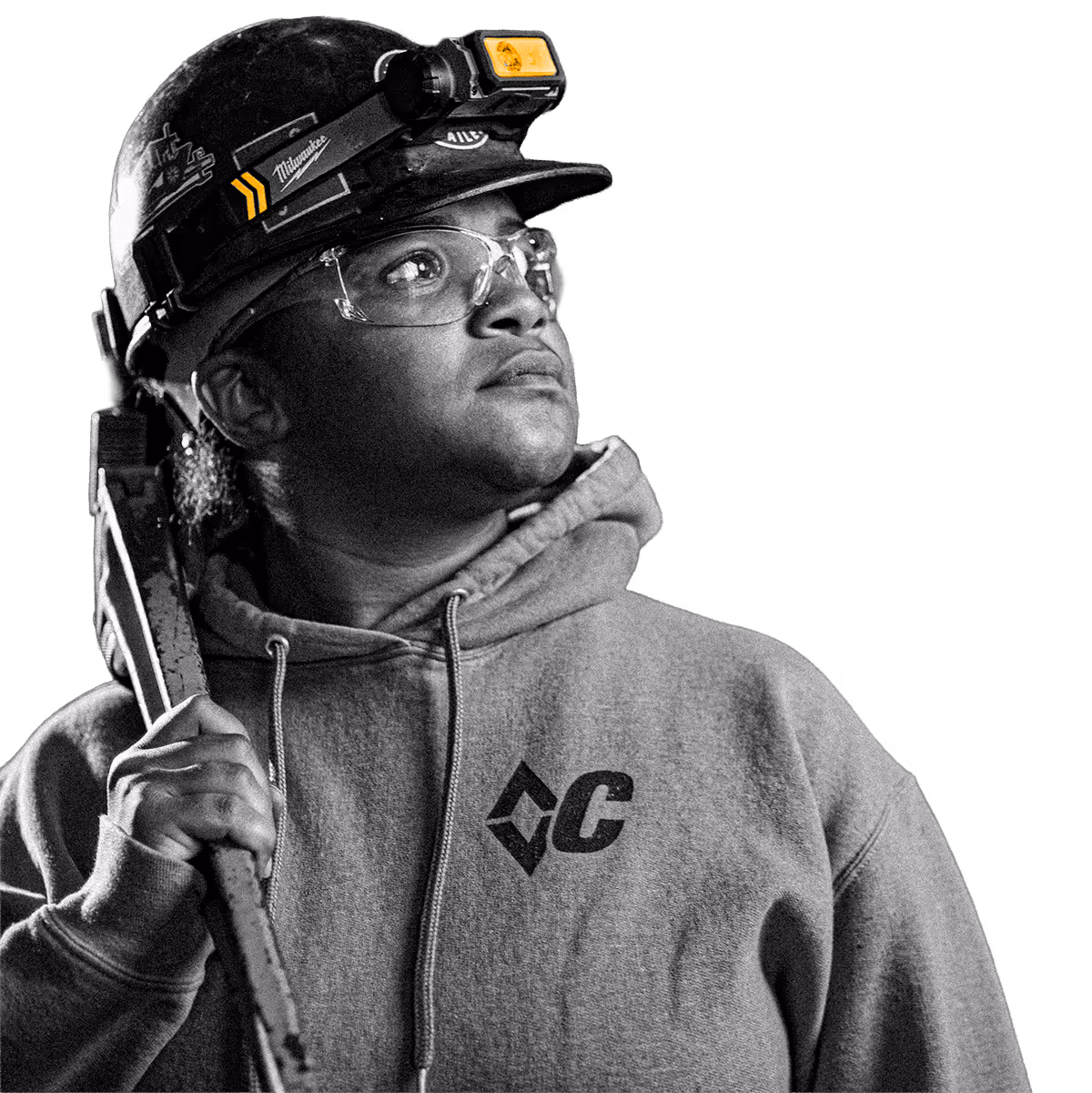 Worker wearing safety helmet and glasses holding a large wrench and looking upward.