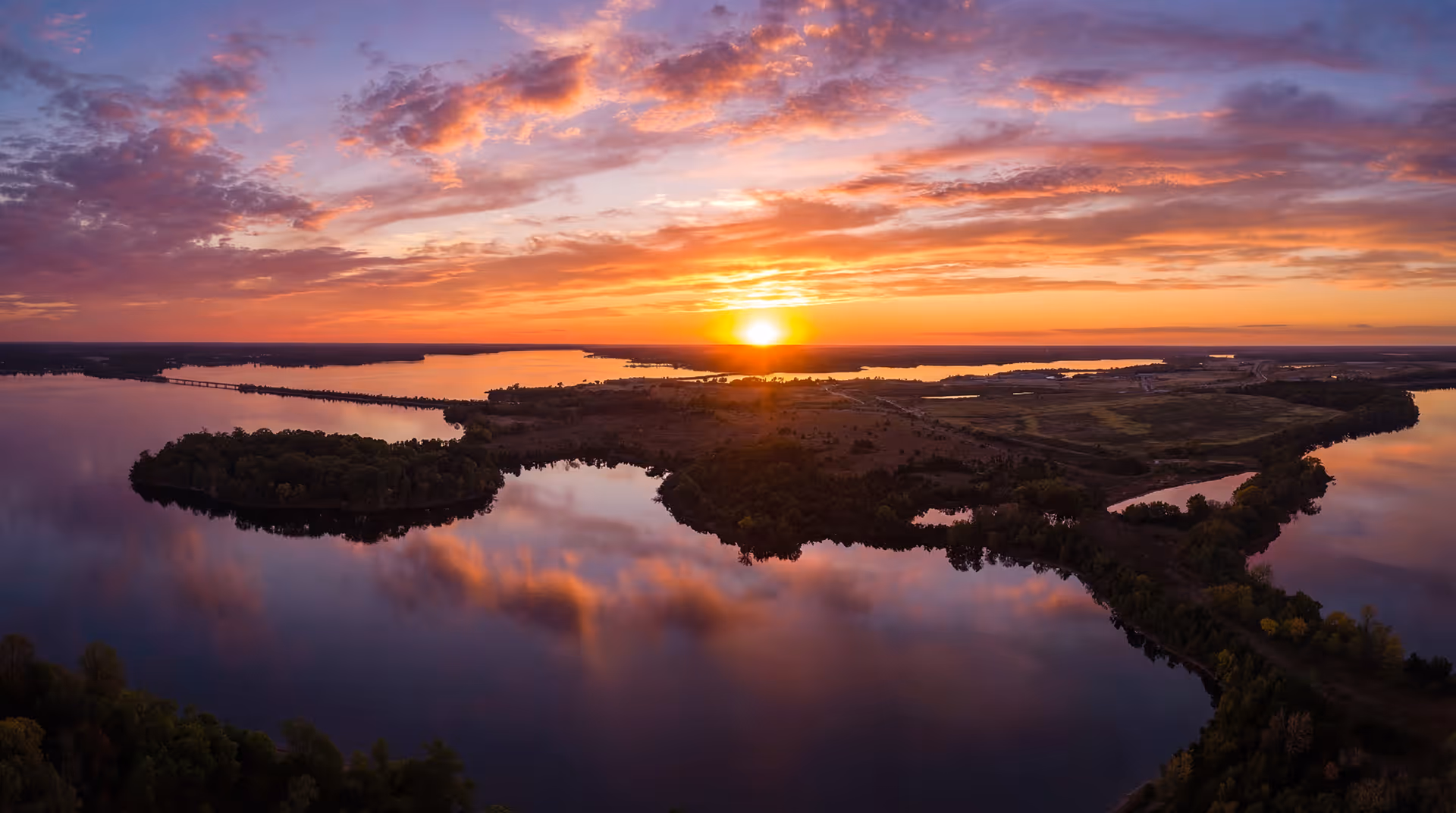 Aerial view of a river and islands at sunset with colorful clouds reflected in the water.