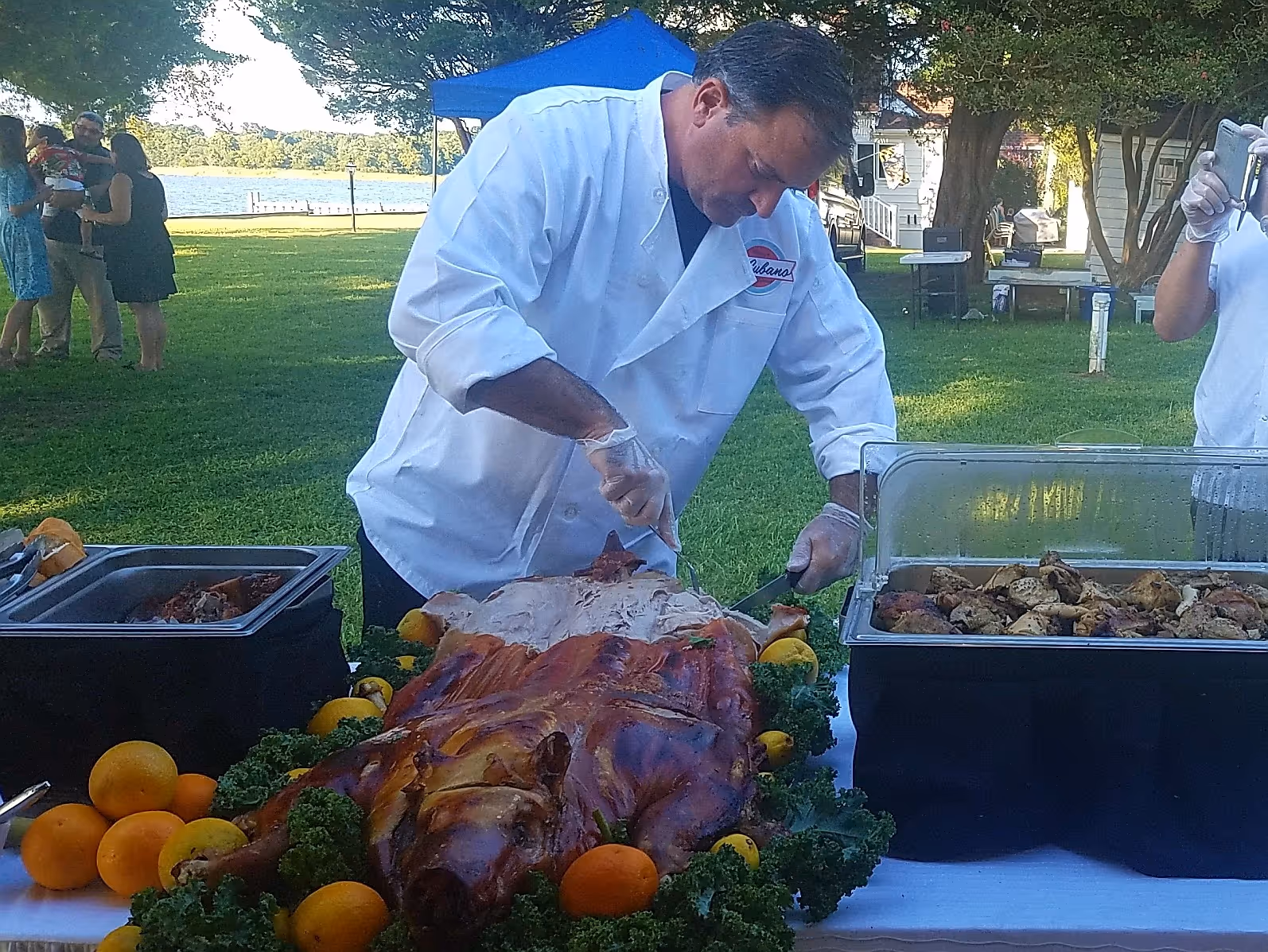 Chef carving a Cuban whole roast pig at tented catering event