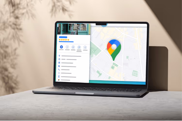 A laptop placed on a light-colored tabletop displays a map interface featuring a colorful location pin, alongside a sidebar with an overview and star ratings.