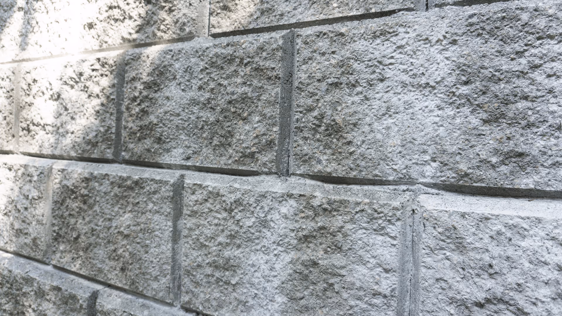 Close-up of a grey concrete block wall with a rough, textured surface.