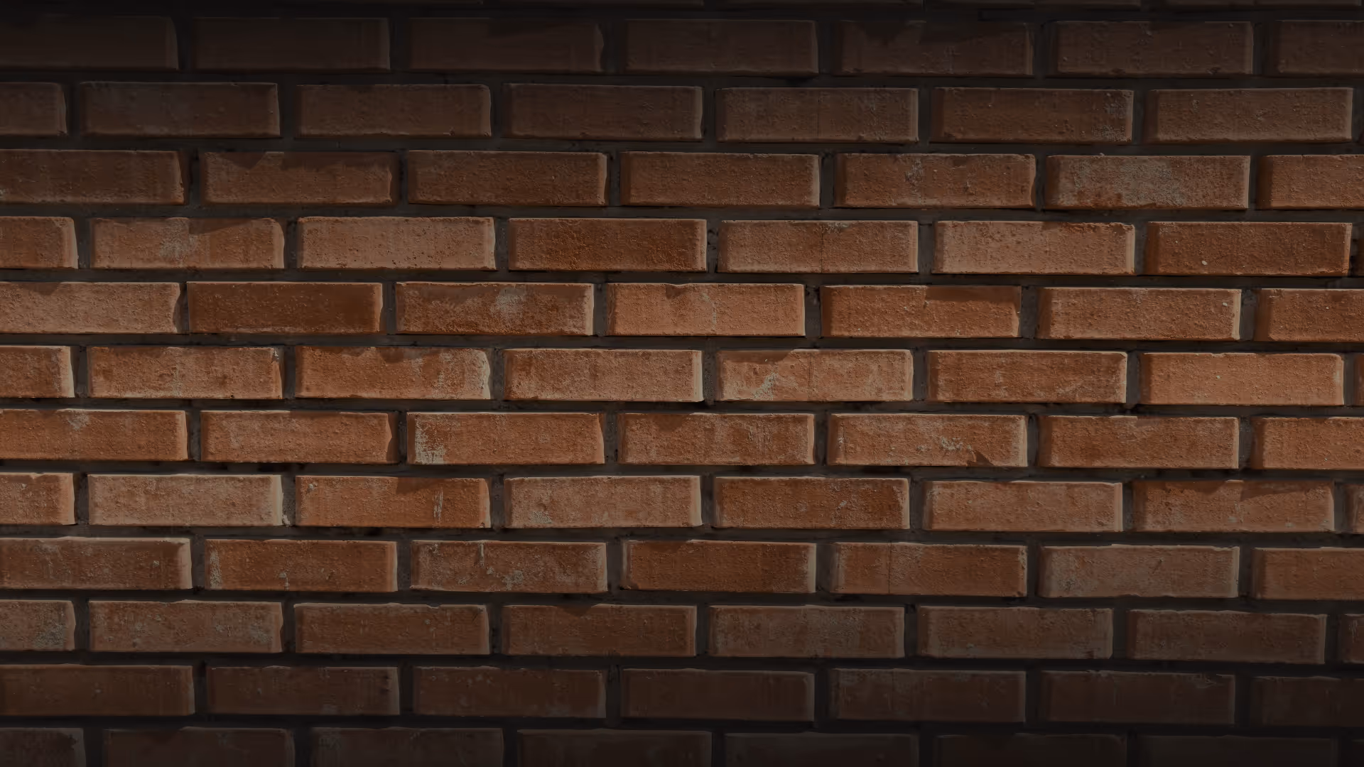 Close-up of a dark brown brick wall with visible mortar lines.