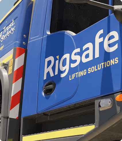 Blue truck door with 'Rigsafe Lifting Solutions' logo and red-and-white warning stripes on the side.