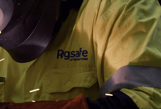 Worker in a yellow Rgsafe uniform welding with sparks flying.