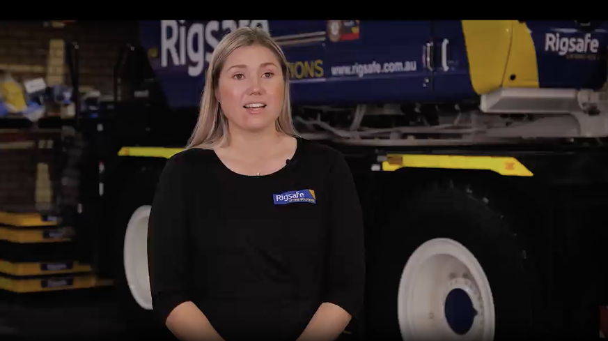 Close-up of a blue and yellow Rigsafe vehicle with 'Lifting Solutions' and safety slogan on the door.