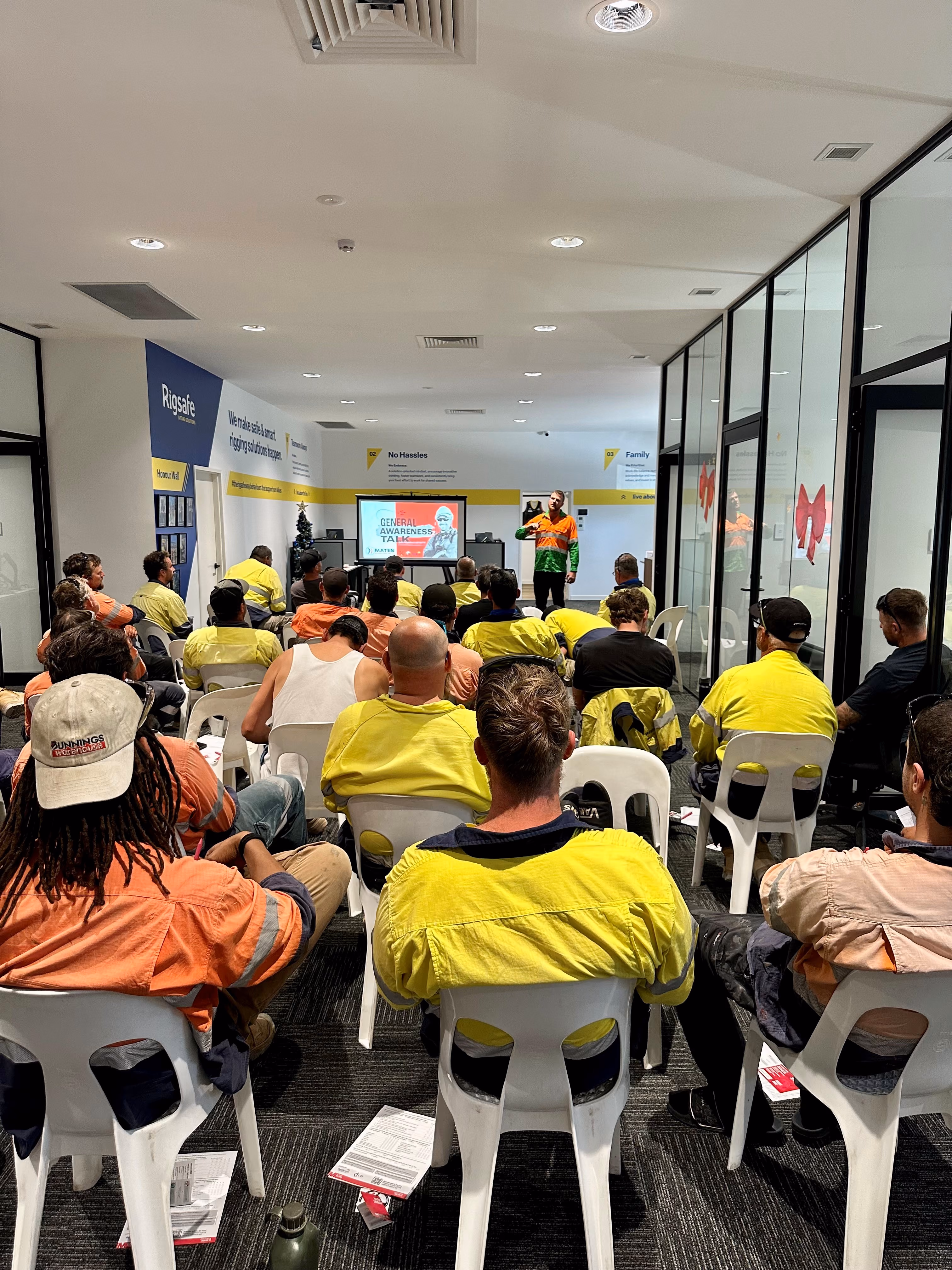 Group of workers in high-visibility clothing attending a safety training session in a conference room.