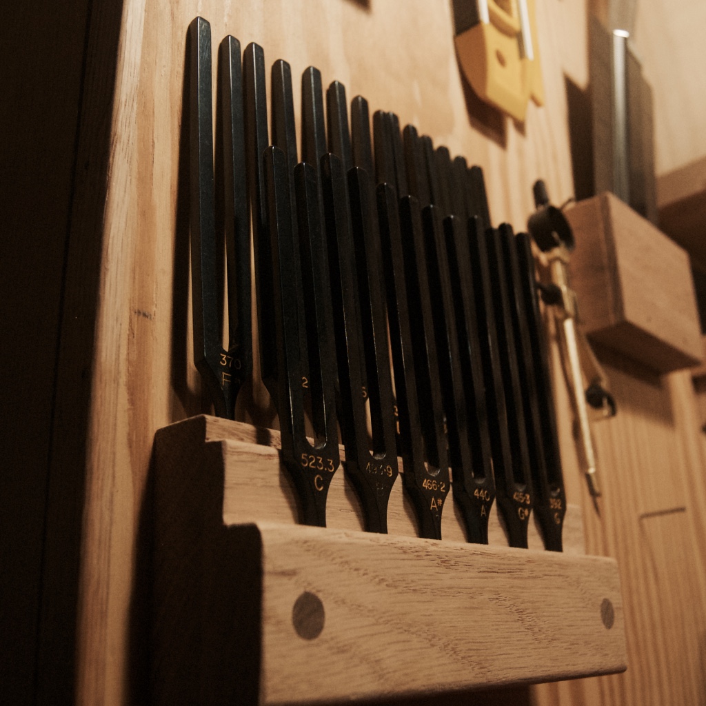 Set of tuning forks stored in a wooden holder.