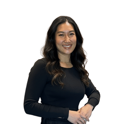 Smiling woman with long wavy dark hair wearing a black long-sleeve top against a white background.