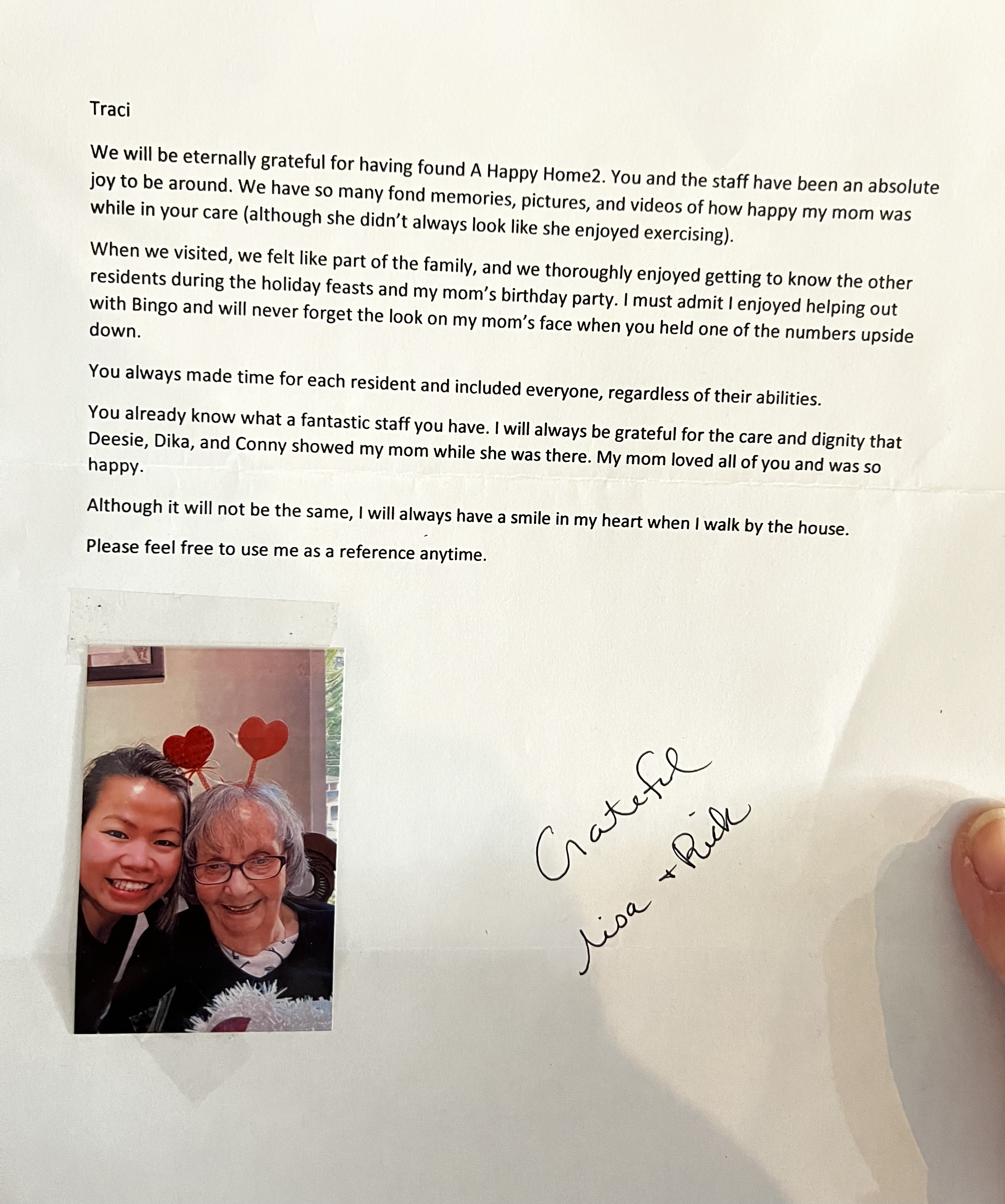 A letter expressing gratitude to the staff of A Happy Home2 for their care, with a small photo of two smiling women wearing heart-shaped headbands taped to the page, signed 'Grateful Lisa + Rick'.
