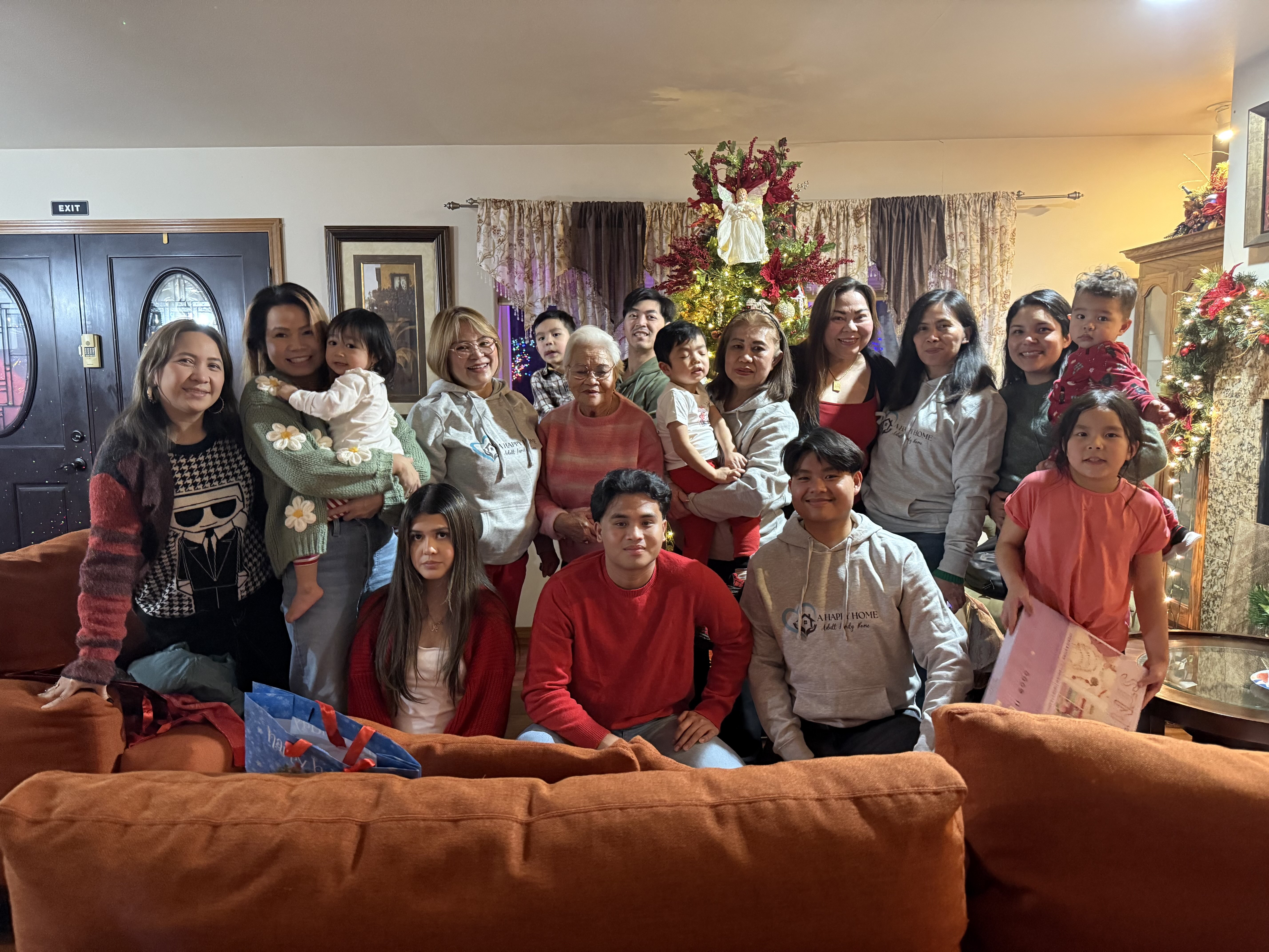 Large family group posing indoors in front of a decorated Christmas tree with children and adults smiling.