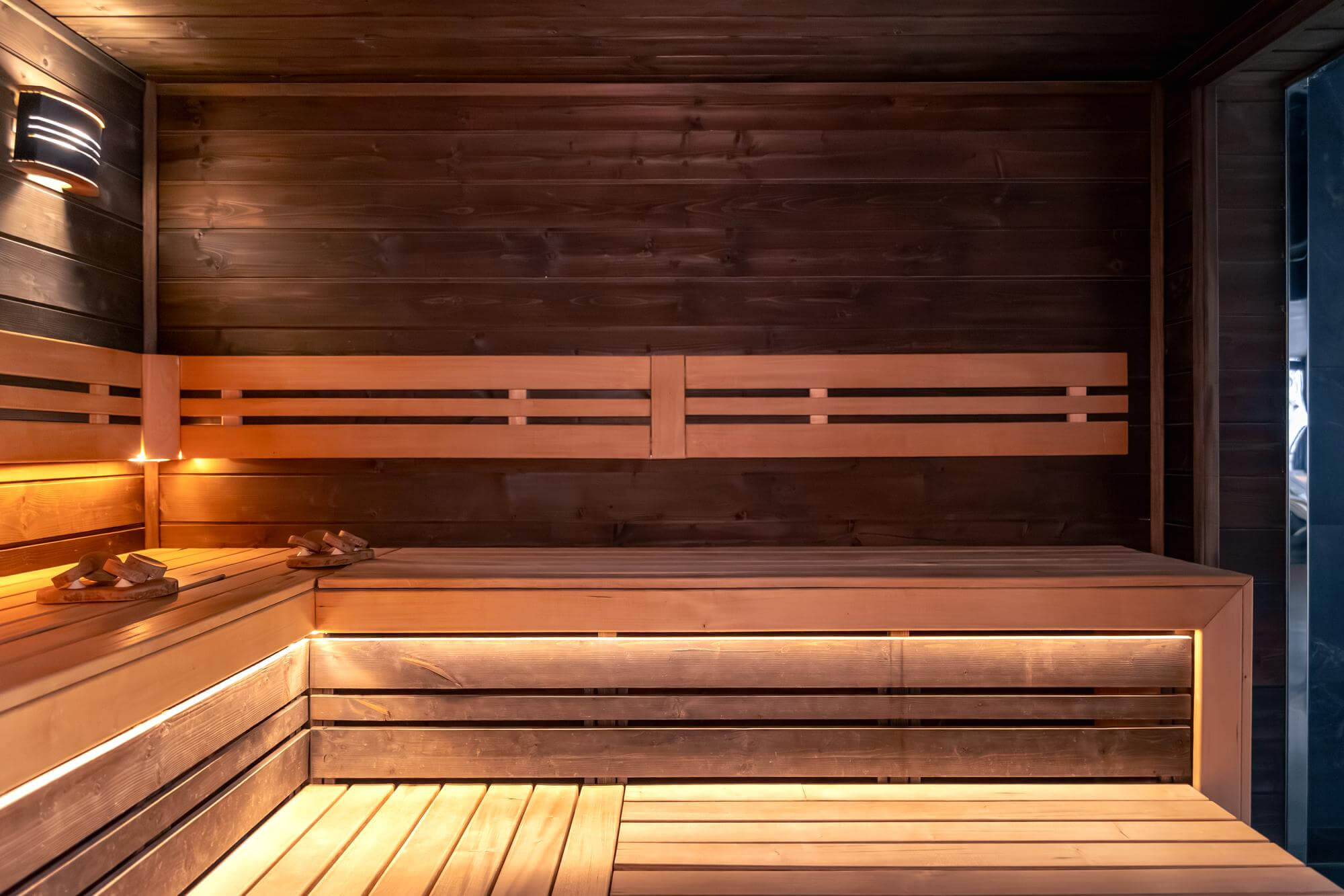 Sauna, jossa on puupenkit, puupaneelit ja pehmeä valaistus.