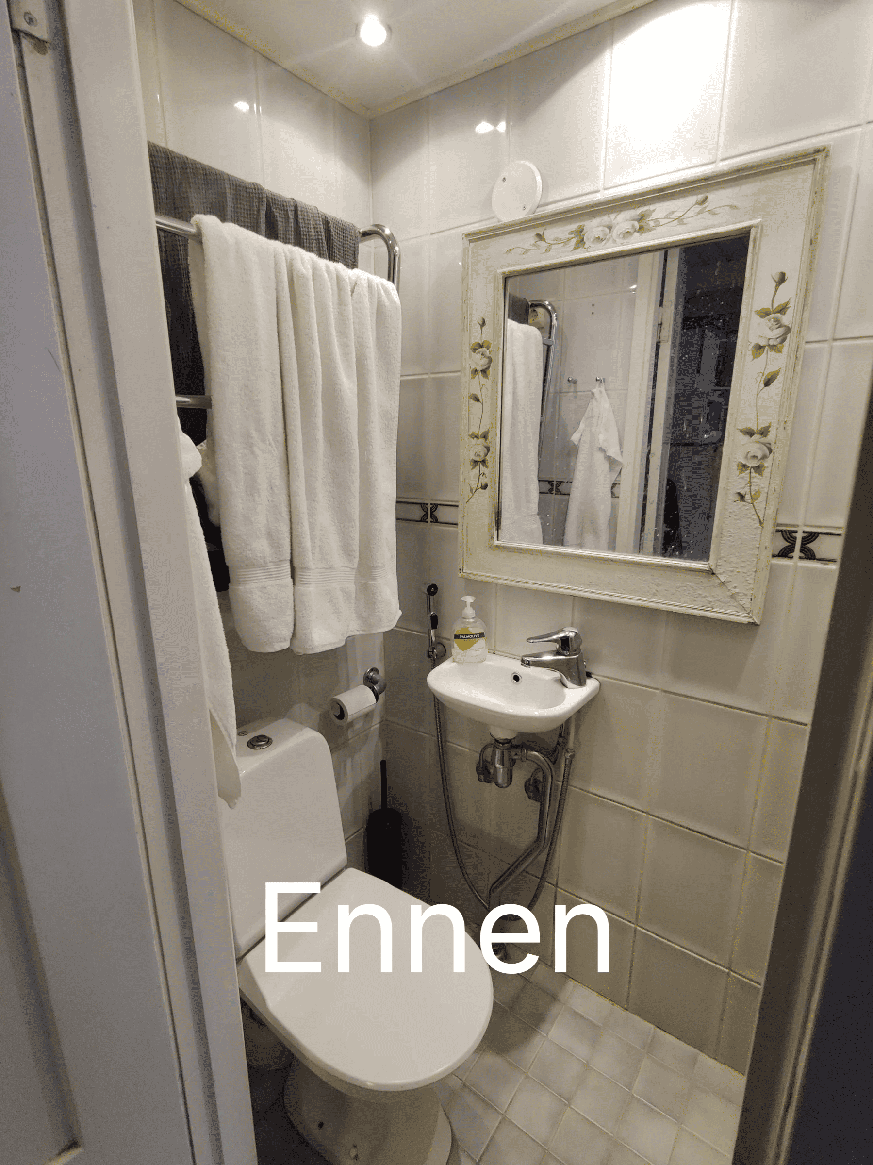 Pieni kylpyhuone, jossa on valkoinen wc-istuin, lavuaari ja peili, valaistus on kirkas.