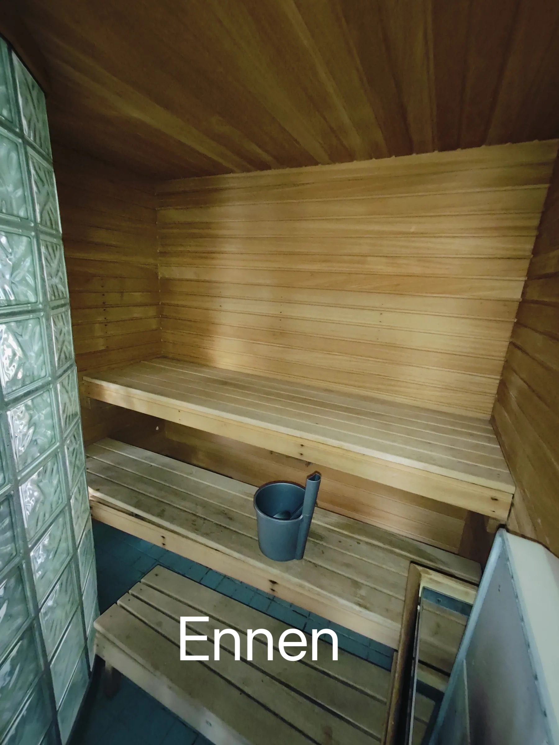 Sauna puupaneeleilla, penkeillä ja kiululla. Valoisa ja lämmin tunnelma.
