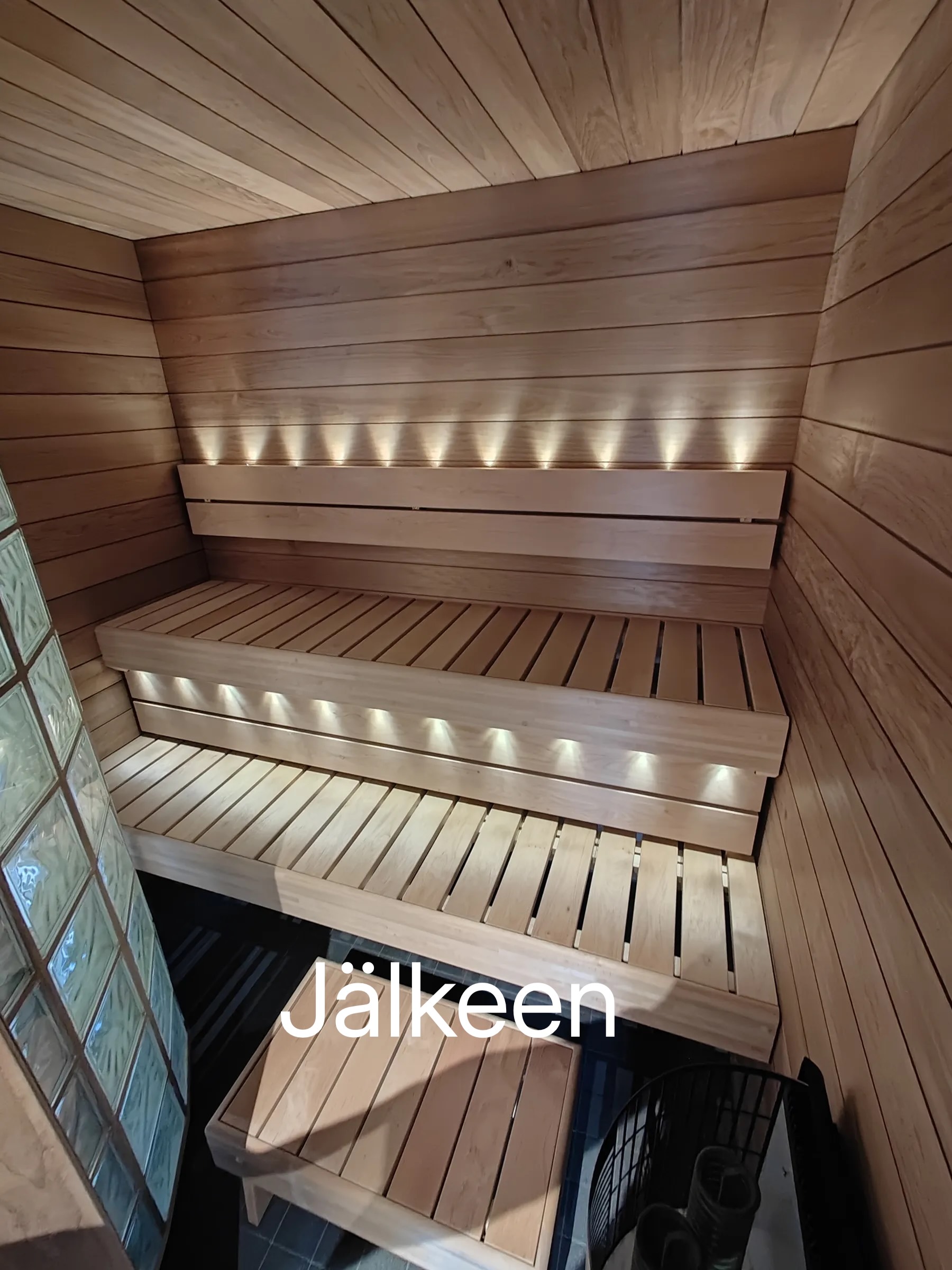 Sauna, jossa on puupanelointi, puiset penkit ja epäsuora valaistus.