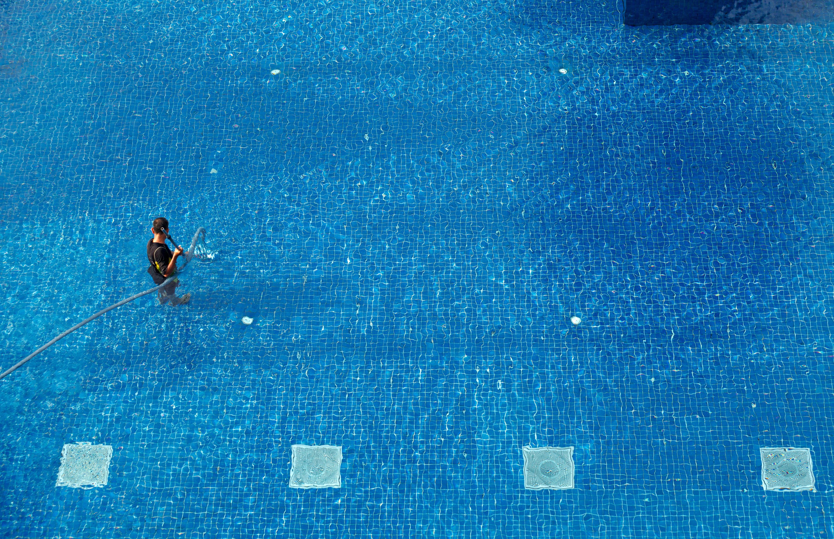 Innovez Engineering maintenance technician vacuums a swimming pool floor to remove any debris and algae.