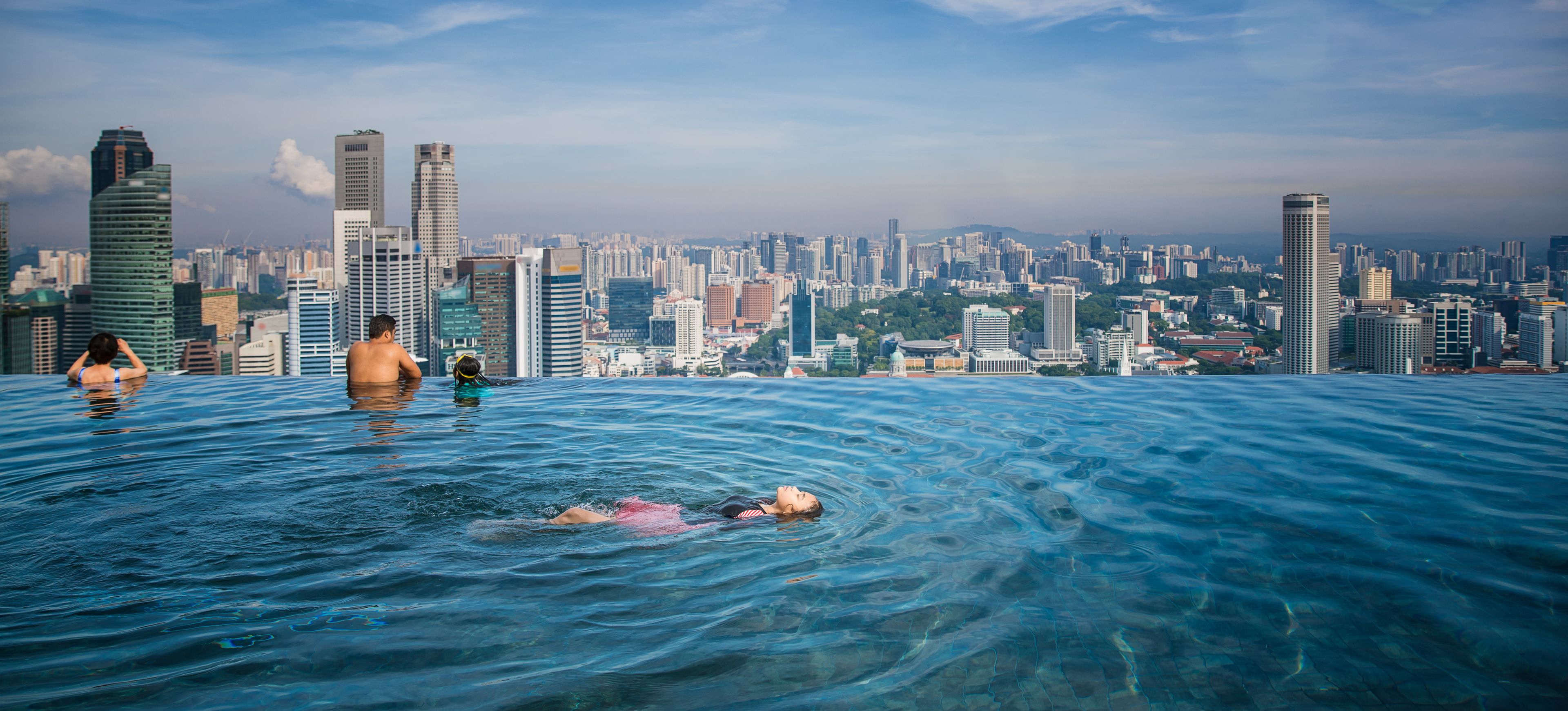 Swimmers float and relax at the Marina Bay Sands SkyPark Infinity pool, which faces towards the panoramic Singapore skyline.