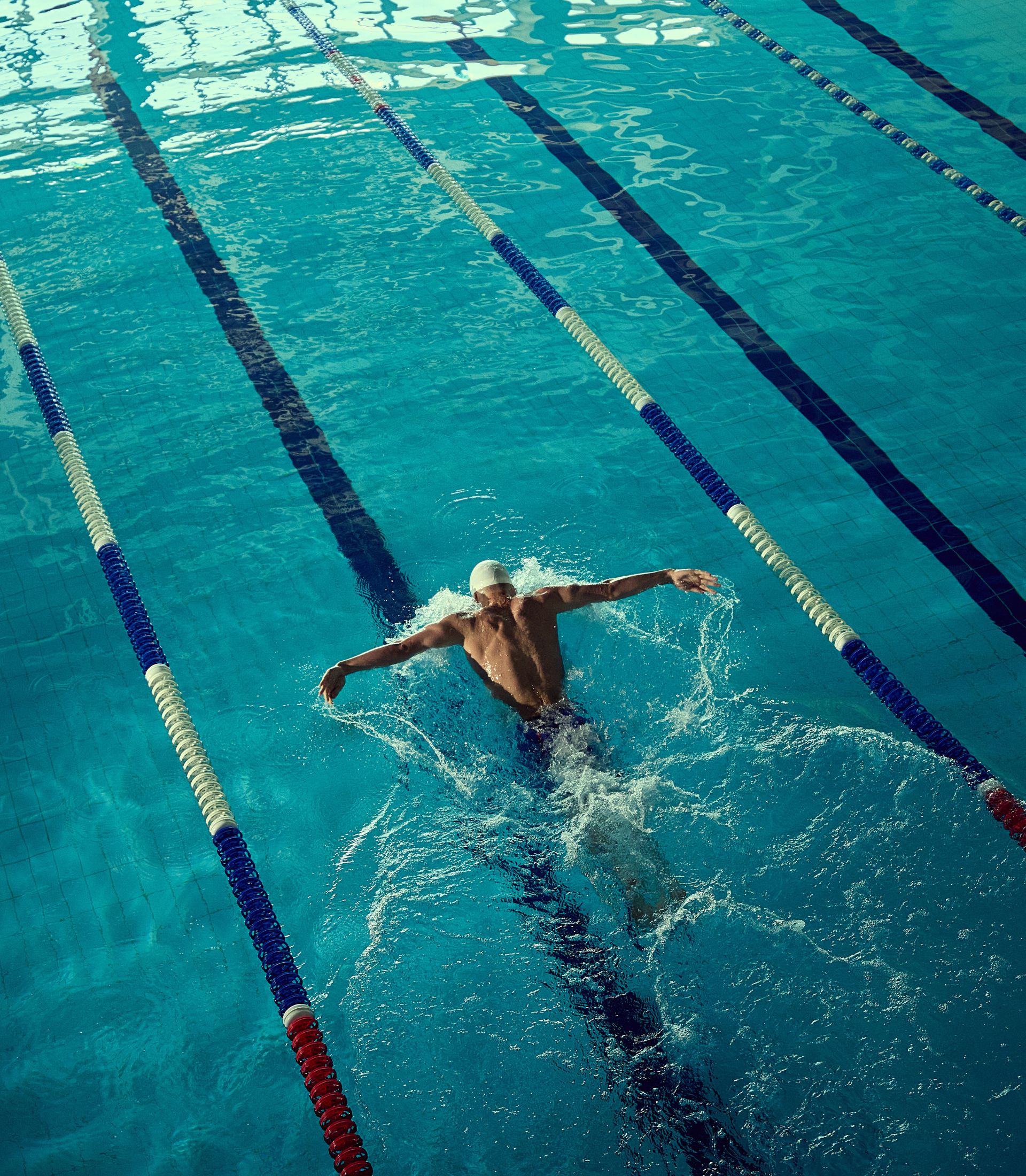 A professional swimmer propels himself forward in a clear pool.