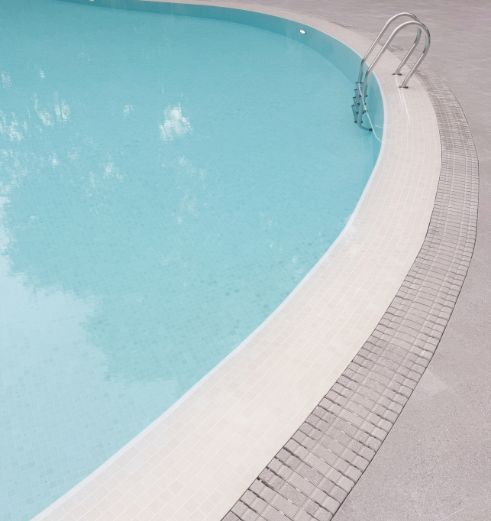 The corner of the swimming pool at The Arcadia condominium in Singapore, with a stainless steel pool ladder.