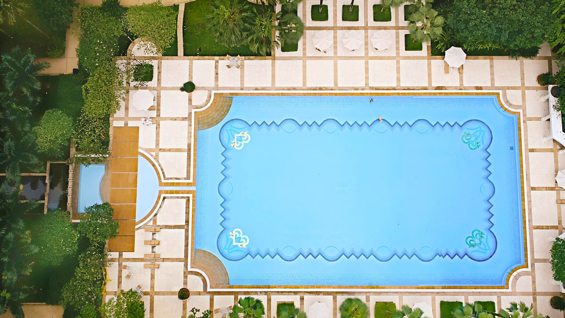 Overhead view of all three swimming pools at Ardmore Park condominium in Singapore. The main 50-metre lap pool stands out; all four corners of the pool are beautifully curved with an entry point of steps on the shallow end, and ladders on the deep end.