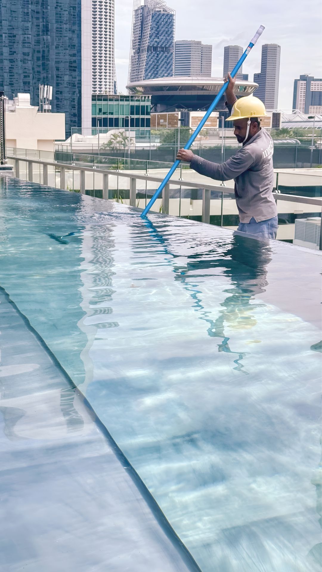 A worker from Innovez Engineering is wearing a helmet, and cleaning the swimming pool at 21 Carpenter hotel.